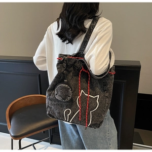 Detail view of denim tote bag with red drawstring and cute white cat print pattern