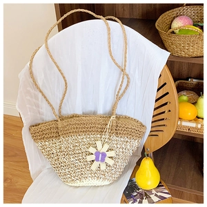 Detail of handwoven tote bag featuring dual-tone natural textures and flower charm