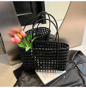 Detail of a black hollow woven beach tote bag with glossy finish on a stylish background