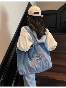 Blue denim tote bag featuring white spider web embroidery with red spider detail