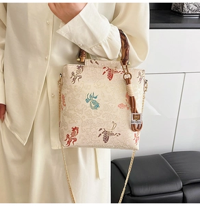 Detailed close-up of embroidered koi fish and butterfly motifs on a textured fabric bag