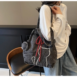 Detail of grey denim tote bag with white cat embroidery and red drawstring accent