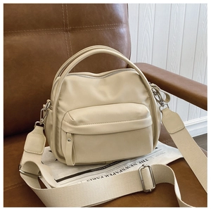Detail of minimalist beige crossbody bag with adjustable wide strap and silver zippers