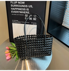 Detailed view of black woven basket bag texture with mesh design on a silver table