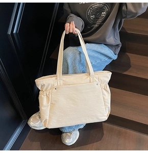 Détail du grand sac cabas crème avec poches frontales et rivets argentés élégants