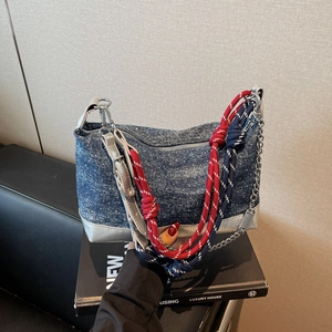 Close-up of blue denim tote with silver leather trim and woven chain strap details