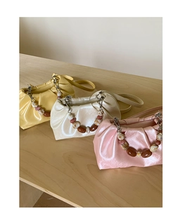 Detailed view of pleated cloud bags in yellow, cream, and pink with beaded handles