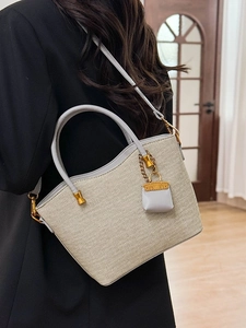 Elegant beige woven tote bag with grey trim worn by model in minimalist black suit