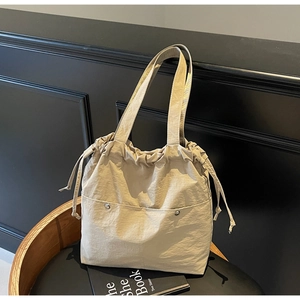 Close-up of khaki drawstring tote bag with silver metal buckles and front pockets