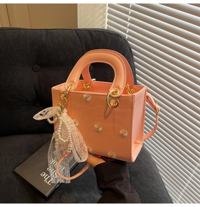 Detail of pink mini tote bag with daisy embroidery, pearl pendant and gold hardware