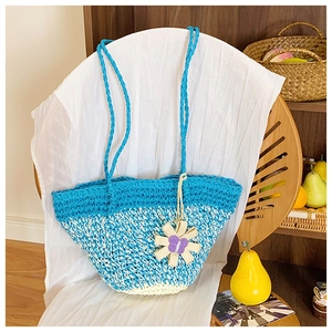 Macro detail of hand-woven straw tote bag with blue and white pattern and floral charm