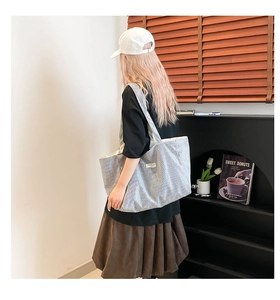 Détail du sac cabas en velours côtelé bleu montrant la texture côtelée et l'étiquette