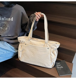 Vue détaillée d'un grand sac cabas beige en nylon plissé avec une poche avant spacieuse