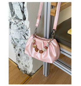 Detail of soft pink pleated bucket bag featuring pearl-finish PU and marble bead handle