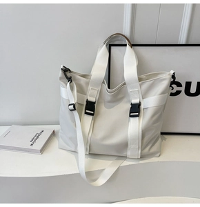 Detail of the cream canvas tote bag showing black buckle straps and textured nylon fabric