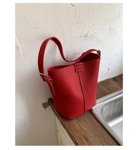 Close-up of red lychee pattern leather bucket bag with vertical stitching and metal buckle