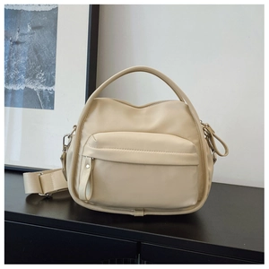 Detail view of beige nylon crossbody bag with front zipper pocket and satin finish texture