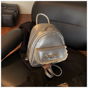 Detailansicht des silbernen Metallic-Rucksacks mit Spitzenbesatz und kleiner Schleife