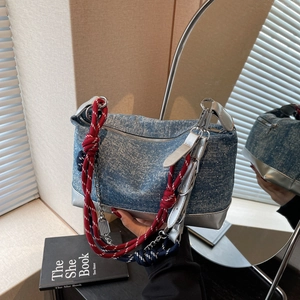Detail of blue denim tote bag with silver leather trim and colorful braided rope strap