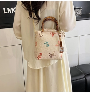 Detail of beaded lace handbag featuring koi embroidery, bamboo handle, and gold chain strap