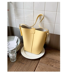 Detailed close-up of yellow lychee pattern leather bucket bag on a wooden surface