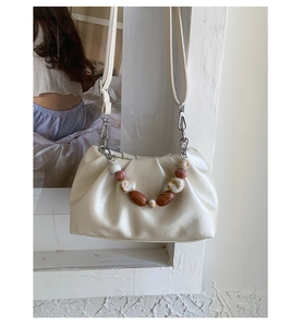 Detail of cream-white ruched cloud bag with marble bead handle and silver hardware
