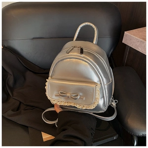 Detail eines silbernen Metallic-Rucksacks mit Schleife und beiger Spitzenborte