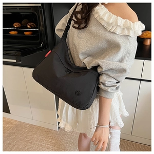 Black large nylon crossbody bag shown in a casual kitchen setting for daily use