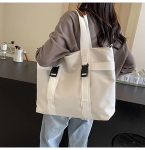 Close-up of white canvas tote bag featuring durable straps and black buckle detail