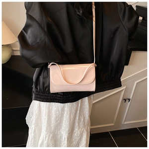 Roze rechthoekige crossbodytas met gebogen klep, gedragen door een model in de kamer