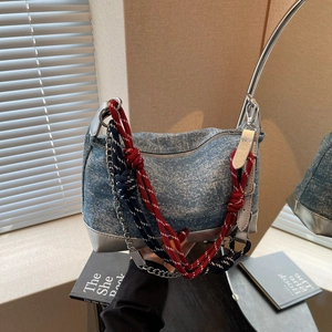 Detail of denim tote bag featuring silver trim, nautical rope strap, and metal chain
