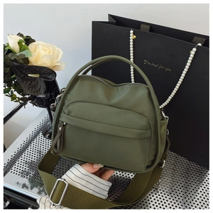 Detail of dark green nylon crossbody bag with front zipper pocket and wide fabric strap