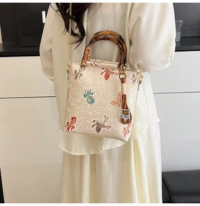 Detailed view of traditional Chinese embroidery on a bamboo handle bag with gold chain strap