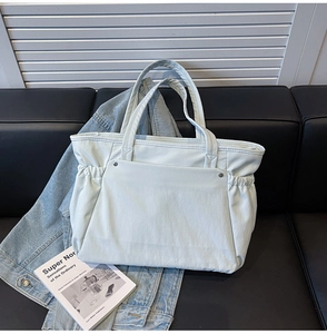 Détail d'un sac cabas en toile bleu clair avec plis latéraux et rivets argentés chic