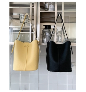 Detail showing yellow and black pebble leather bucket bags with magnetic snap closure