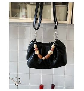 Detail of black pleated cloud bag featuring marble beads and a beaded handle detail