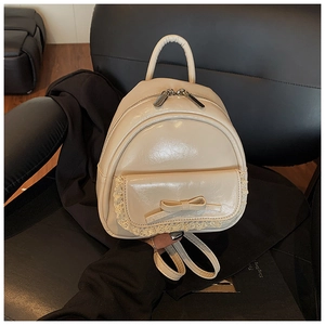 Detail eines cremefarbenen Mini-Rucksacks aus glänzendem PU-Leder mit Spitzenschleife