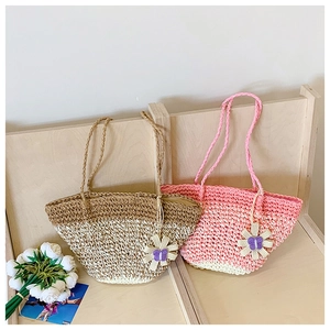 Detail of handmade straw tote bag with floral charm and natural weave texture