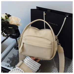 Detail of beige nylon crossbody bag featuring top handle and elegant faux pearl chain