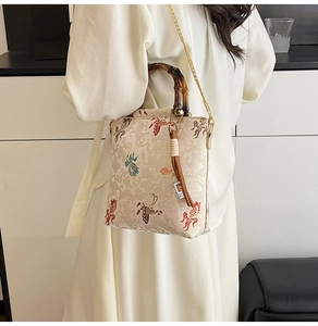 Detail showing embroidered koi and cloud patterns with dark bamboo handles on the bag