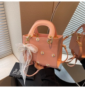 Detail of pink shoulder bag with daisy embroidery and lace bow pearl charm