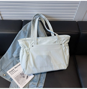 Détail du sac cabas en denim bleu avec rivets argentés et cordon de serrage latéral