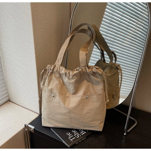 Detail view of khaki drawstring tote bag with dual front pockets and soft nylon texture