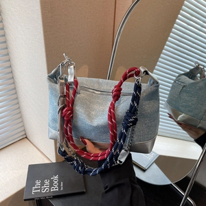 Detail of light blue denim tote with red rope strap and silver leather bottom trim