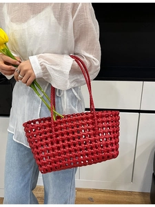 Red woven hollow beach tote bag for summer vacations featuring minimalist basket style handles