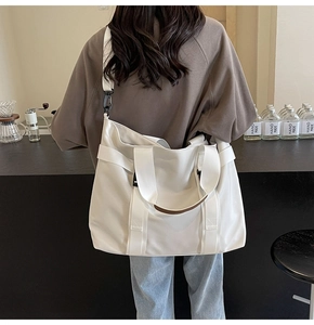 Model view of large white canvas tote bag with adjustable strap in casual urban setting