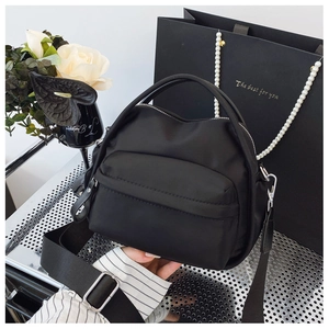 Detailed shot of black nylon crossbody bag with adjustable wide strap and silver hardware