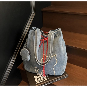 Close-up of denim tote bag with cat embroidery, red drawstring and mini coin purse