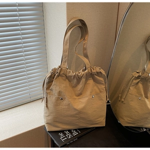 Macro detail of khaki drawstring tote bag with nylon fabric texture and metal studs
