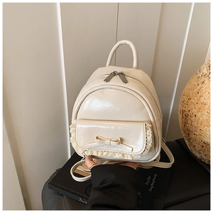 Detail eines cremefarbenen Mini-Rucksacks mit Lederschleife und Spitzenbesatz auf der Klappe